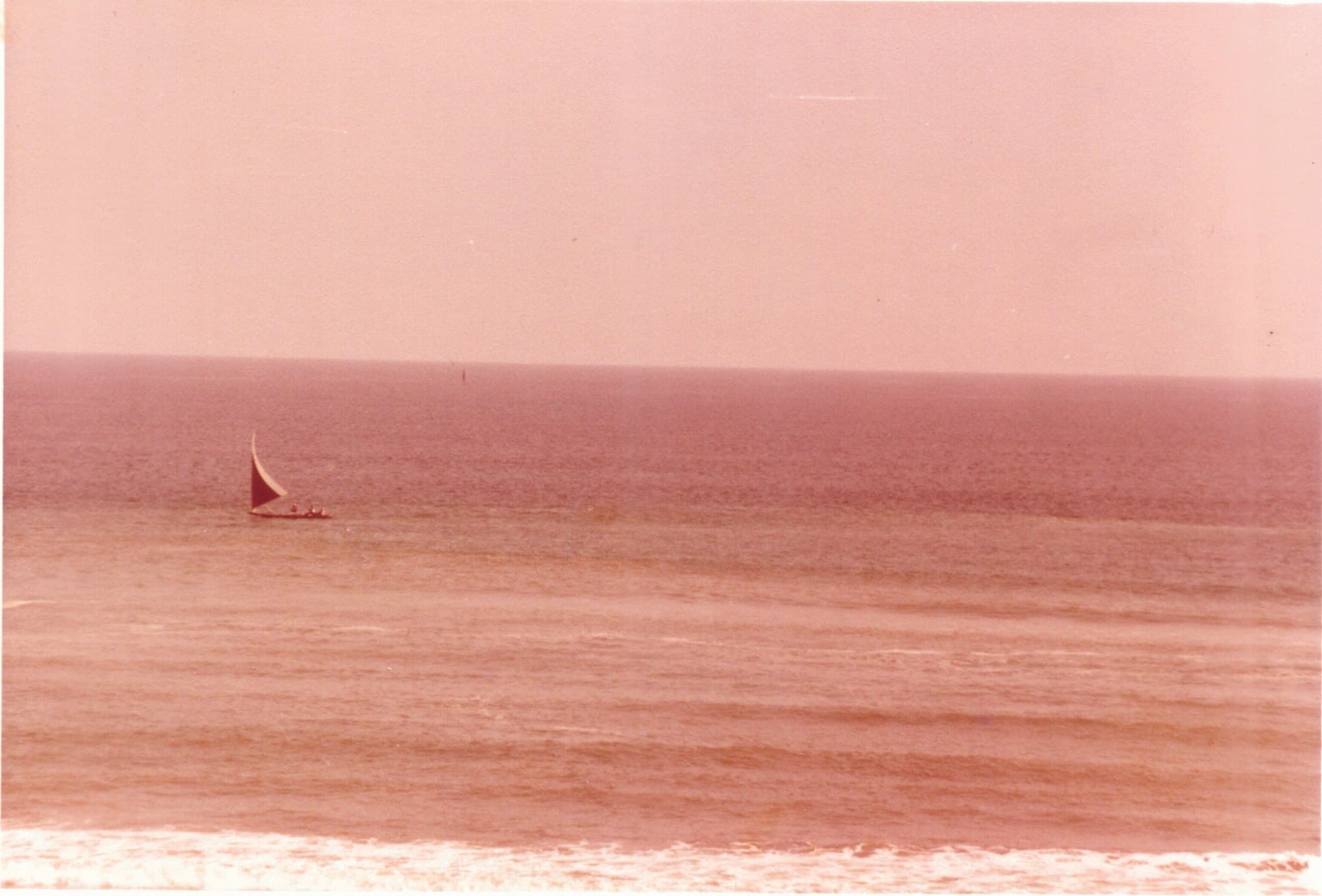 An archive photograph of a sailboat on a calm sea.