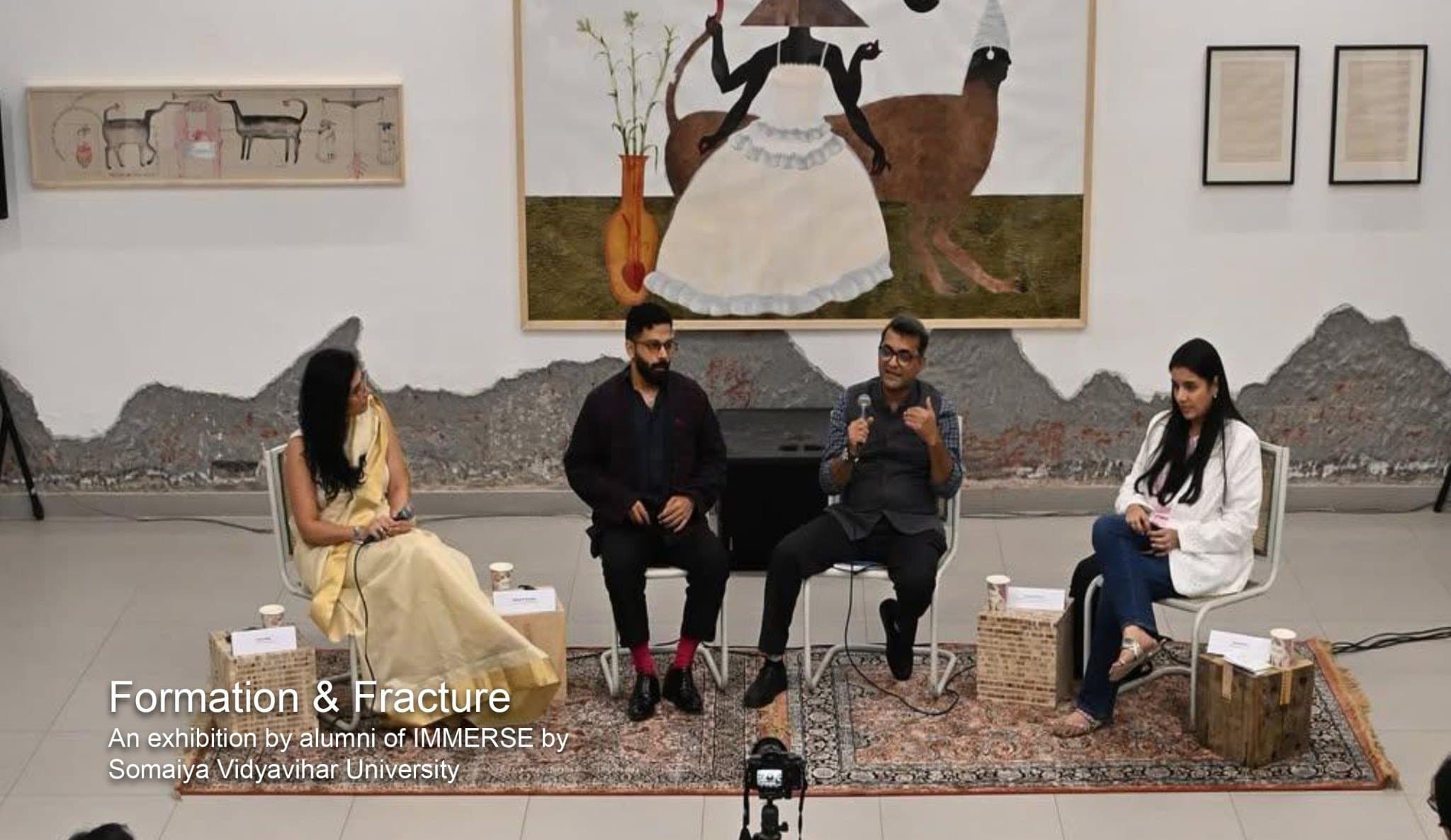 Four speakers seated in conversation in front of paintings at Method Delhi.