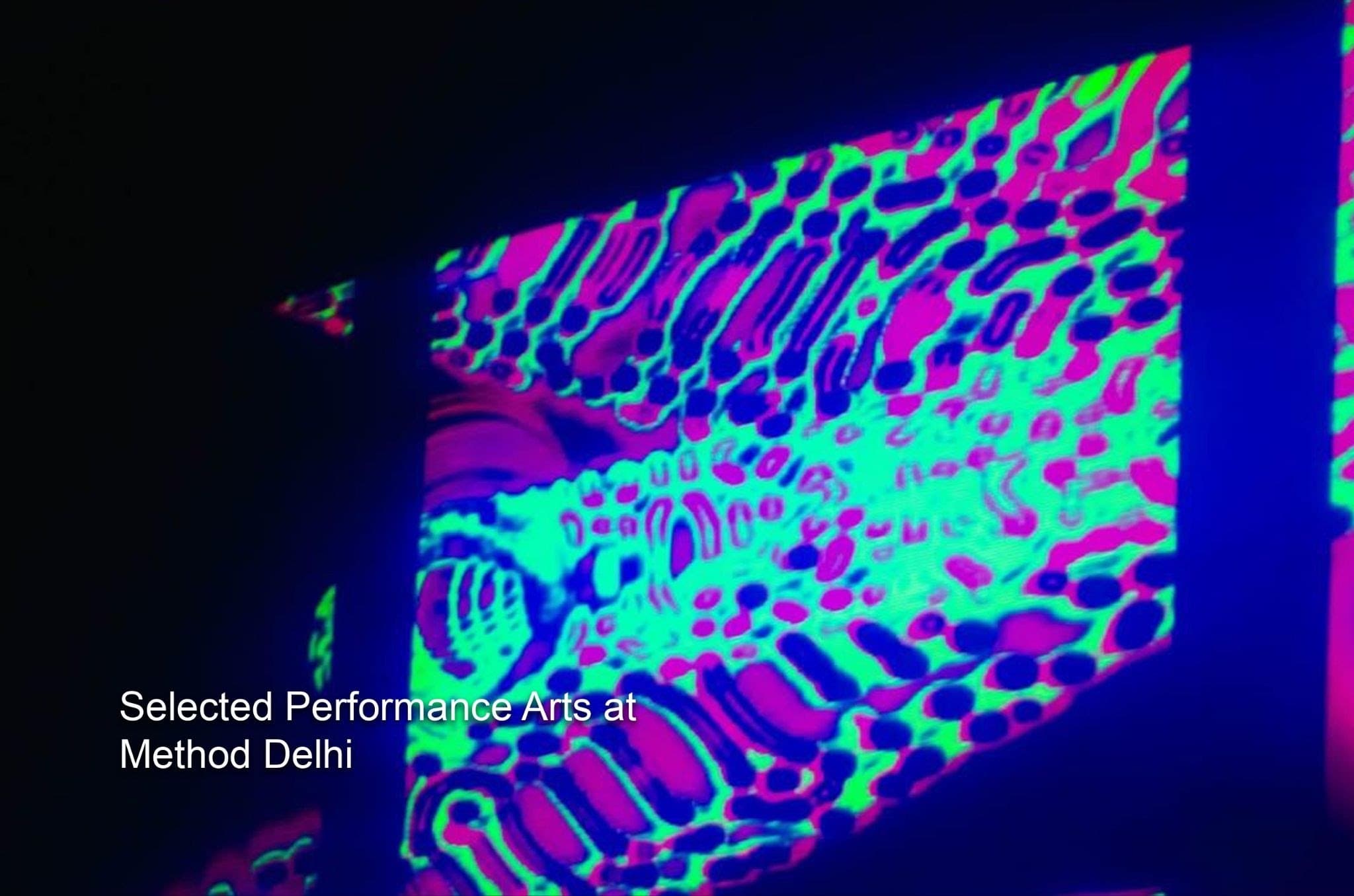 A projection of green and magenta patterns across a dark wall at Method Delhi.